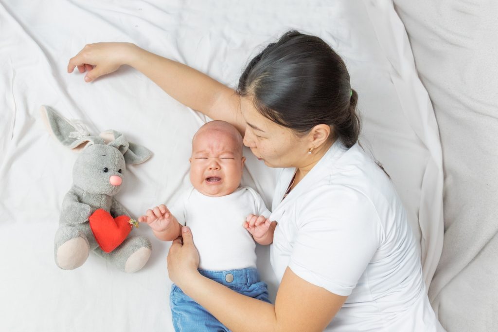 baby is crying and the mother calms him down. Baby and mom at home, lifestyle.