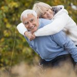 Smiling senior giving his wife a piggyback